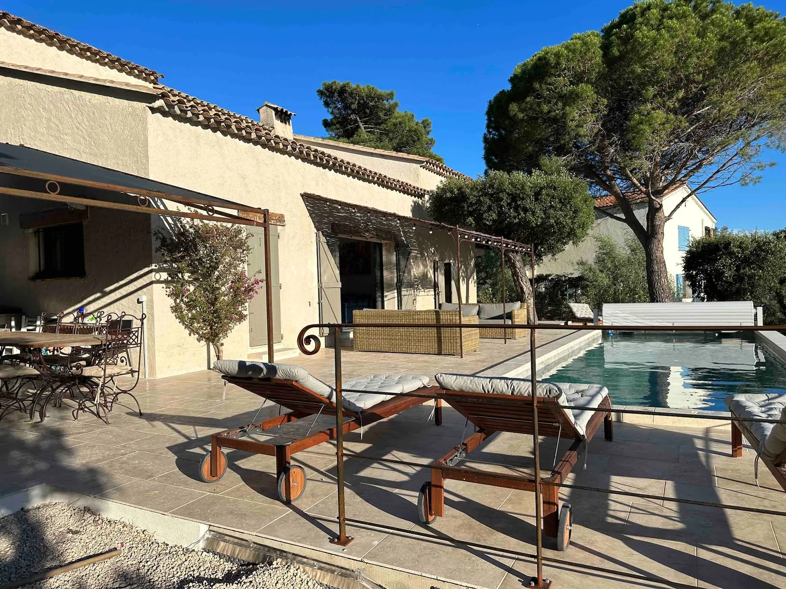 La villa, sa terrasse et la piscine sous les pins